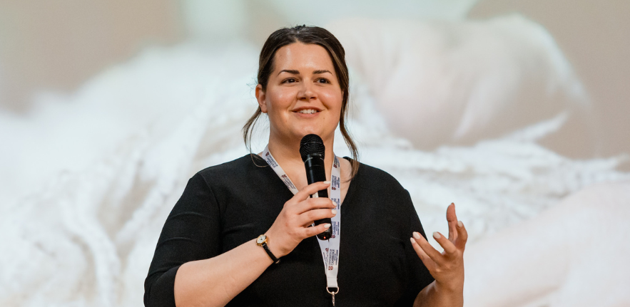 Emma Fromberg stood in front of a presentation with a microphone in her hand