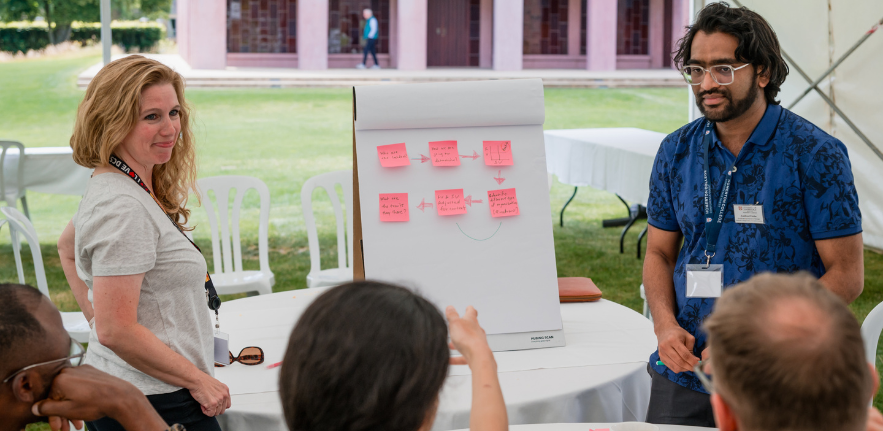 PCSB workshop Students stood around a flipchart presenting