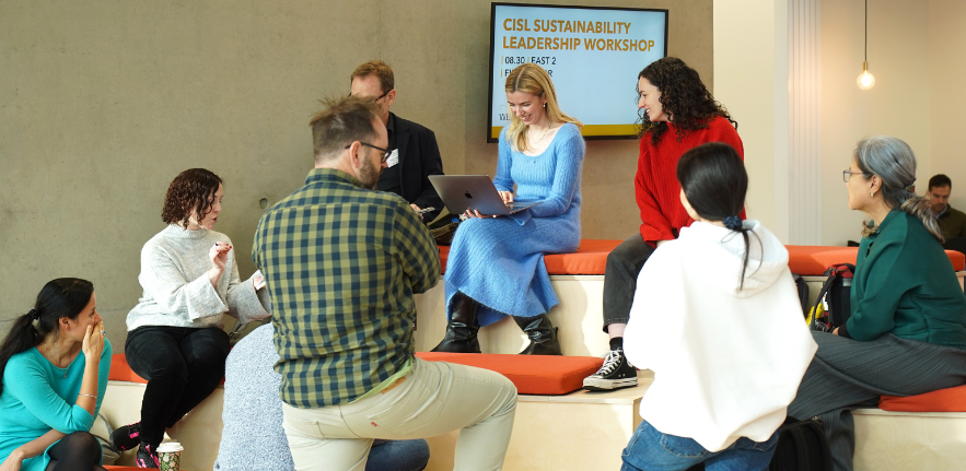 Eight students sat on a mixed level seating area discussing their work