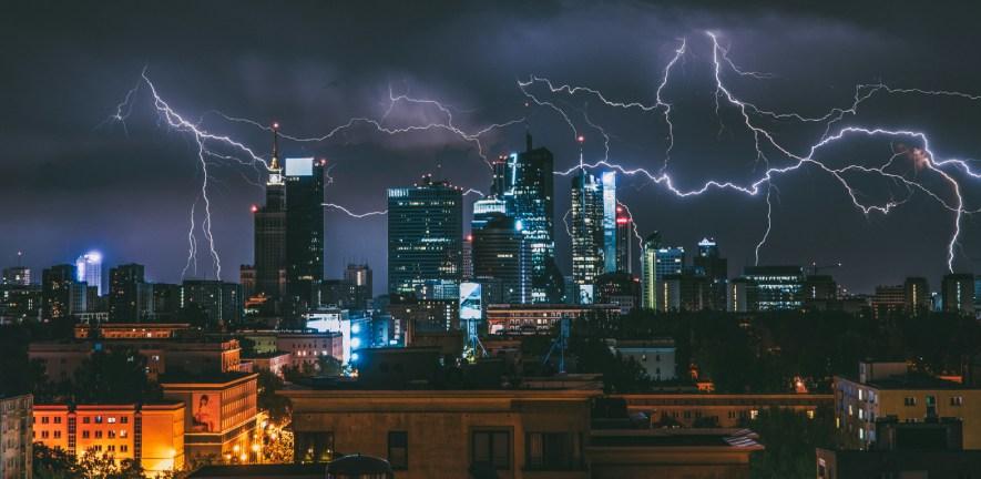 Cityscape at night with flashes of lightning over skyscrapers